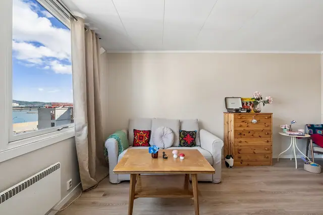 Koselig stue med store vinduer og lysinnslipp.