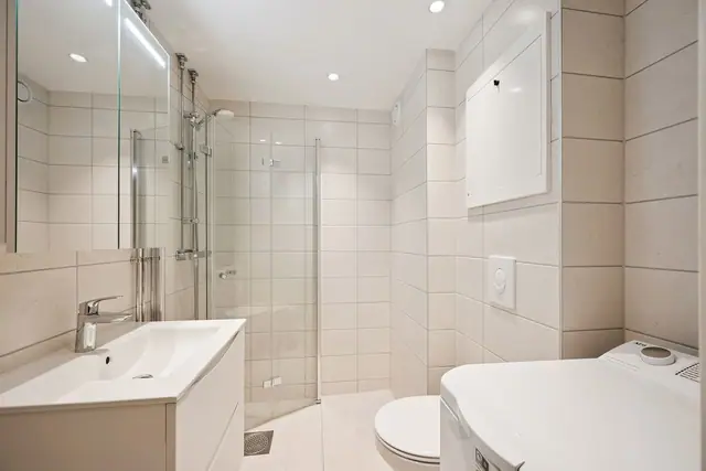 Delikat bad med moderne innredning og opplegg for vaskemaskin.