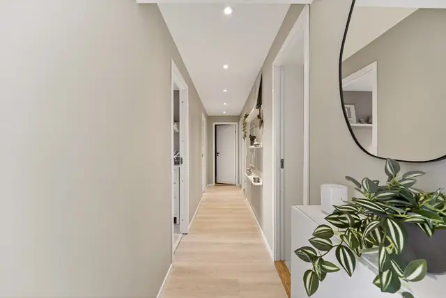 Moderne fargevalg, lys laminat og gjennomgående downlights bidrar til et stilrent uttrykk.