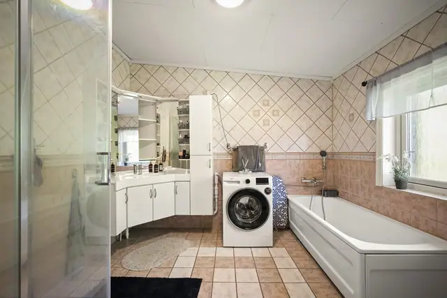Romslig baderom med både dusjløsning og badekar.