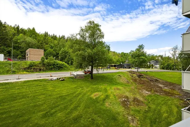 Trivelig utsikt fra leilighetens balkong, bussholdeplassen kan skimtes i bakgrunnen.