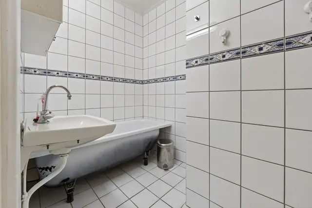 Bad med flislagte overflater, servant og badekar.