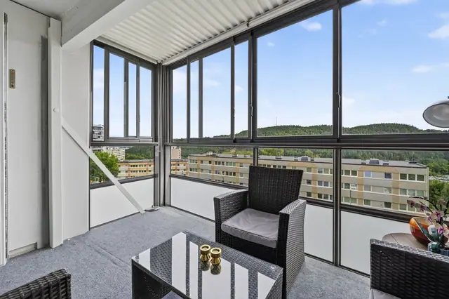 Innglasset balkong med god plass til sittegruppe og pent utsyn.