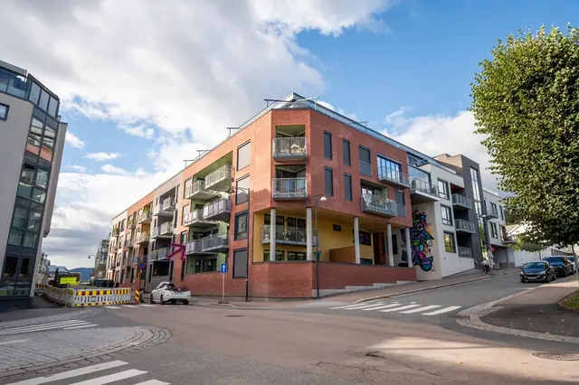 Flott fasadebilde av bygget, med moderne arkitektur, teglfasade og hyggelig bymiljø rundt!