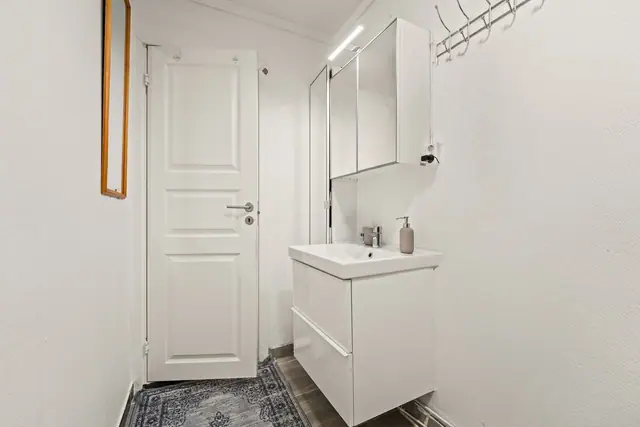 Badet er utstyrt med servant i innredning, speil med belysning, høyskap og overskap, en funksjonell løsning for hverdagen!